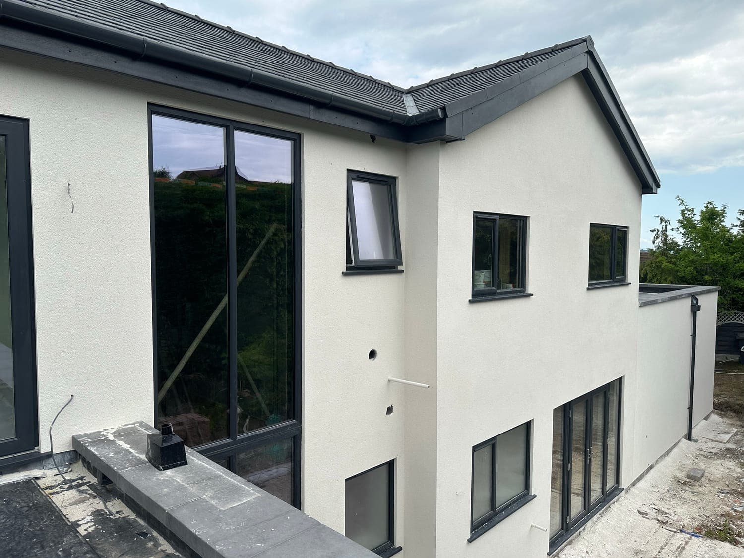 Contemporary house finished in white render, with full-height dark grey windows