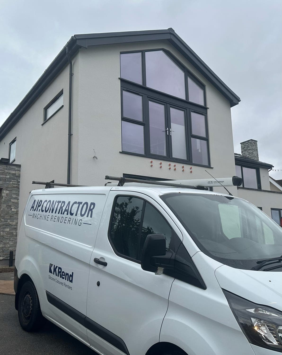 AJP Contractor van parked outside a house finished in white render with dark grey windows