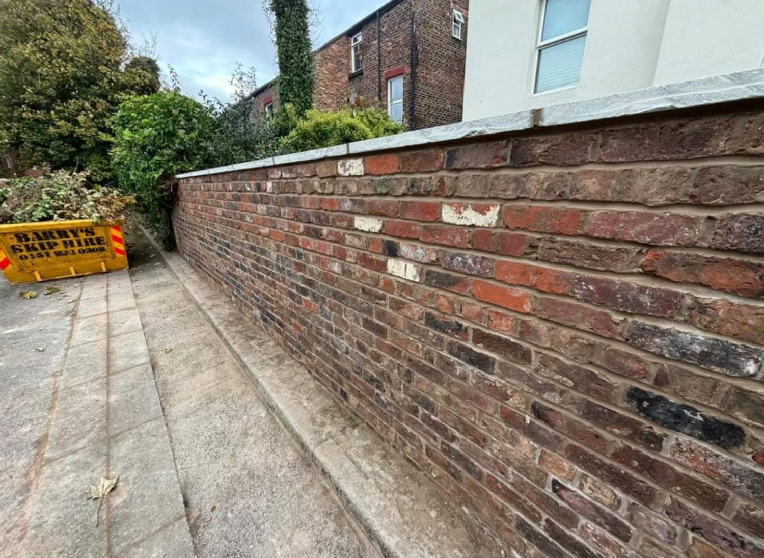 Rebuilt brick boundary wall running the length of a shared driveway