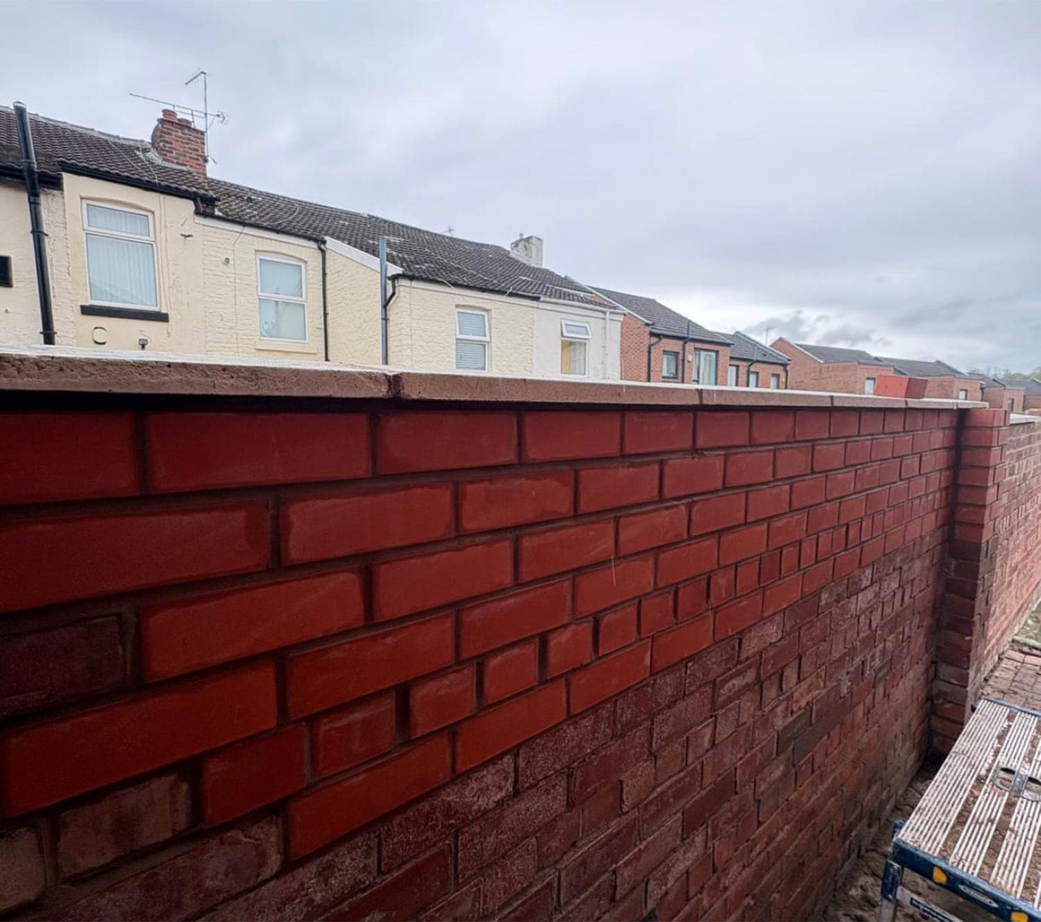 New red brick front boundary wall built along a terraced street