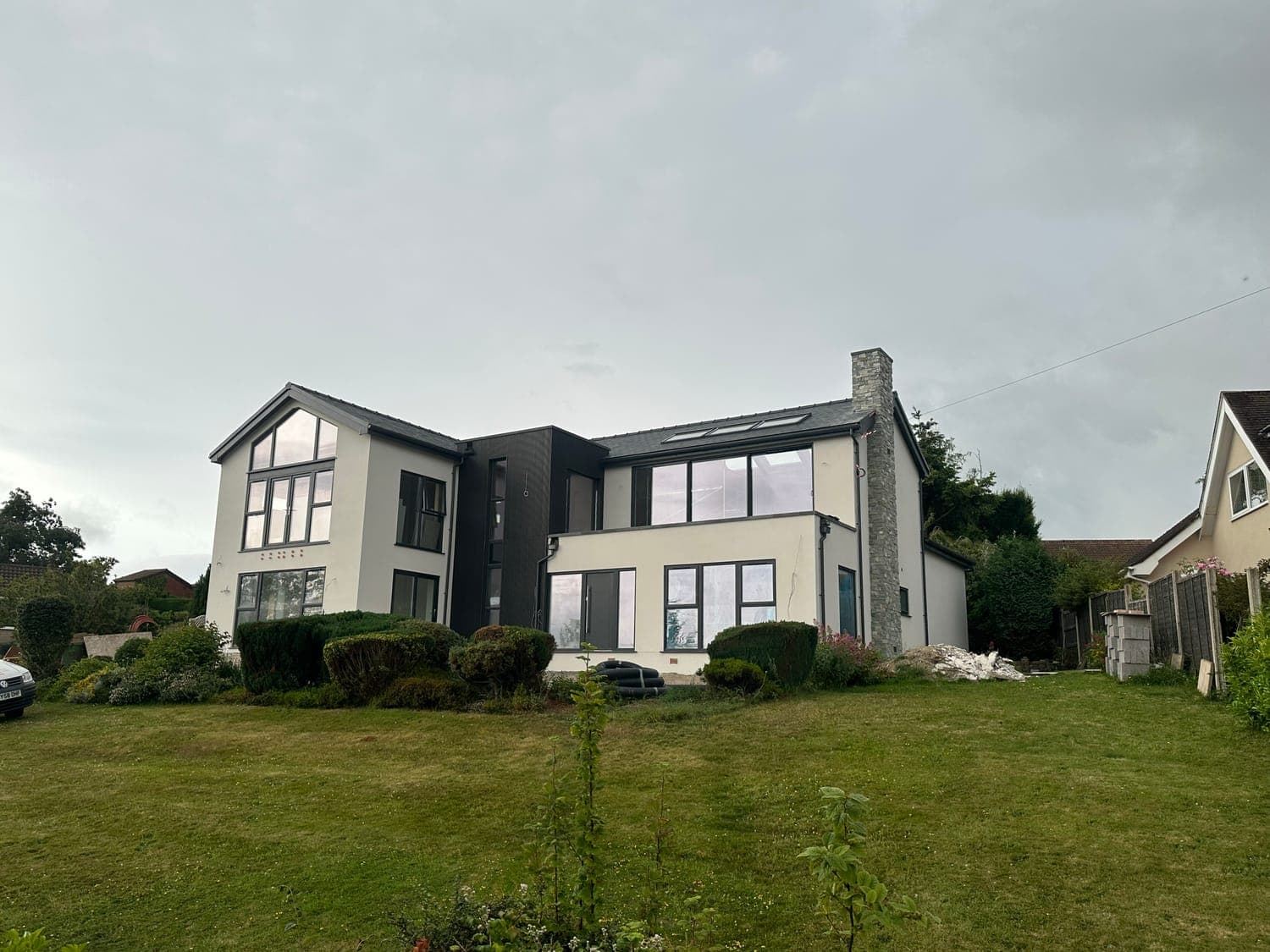 Contemporary house finished in cream monocouche render with dark grey cladding panels