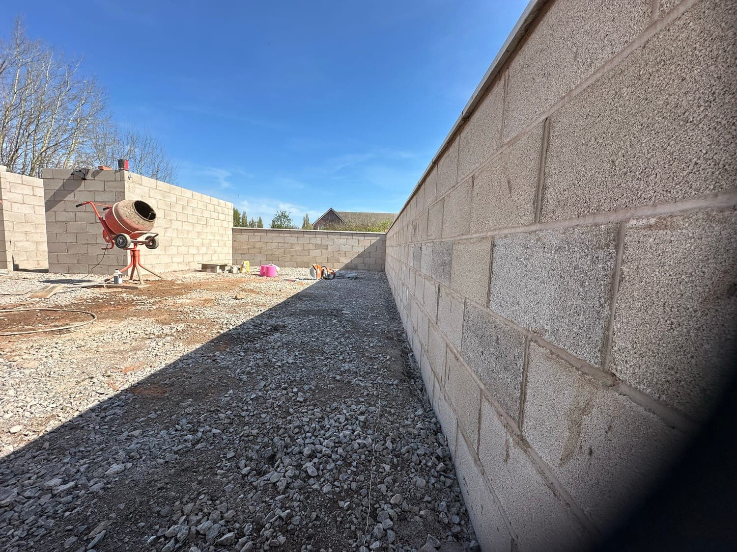 Blockwork retaining walls built out to enclose a new garden, mixer on site