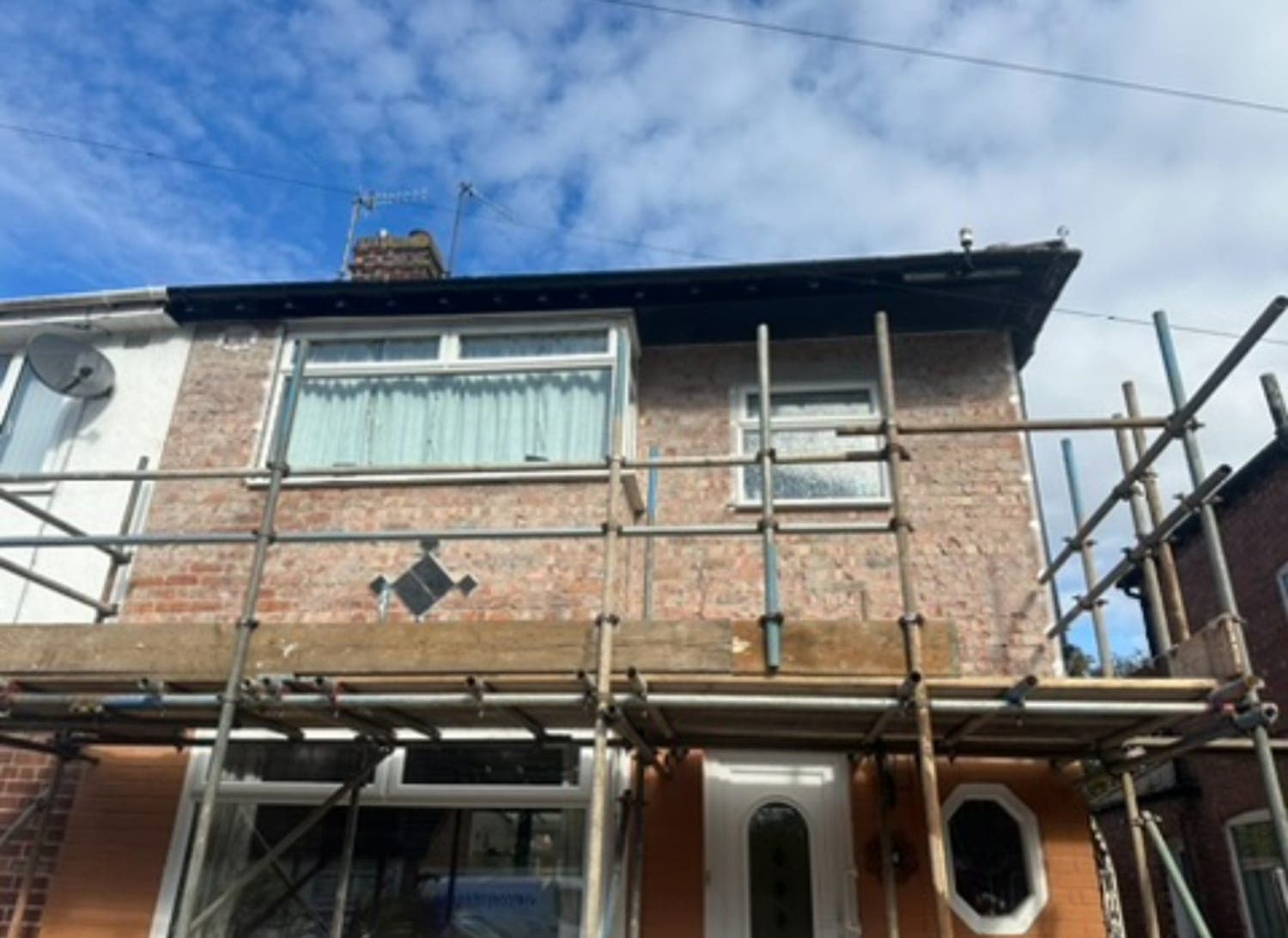 Upper storey of a semi-detached house in bare brickwork before rendering
