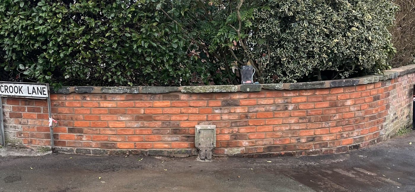 The same boundary rebuilt as a curved brick wall with a neat coping course