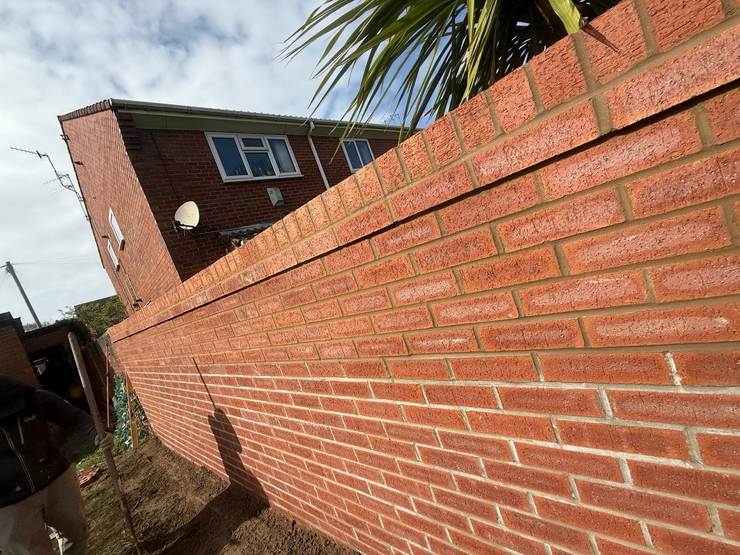 Newly built red brick boundary wall with a brick-on-edge coping course