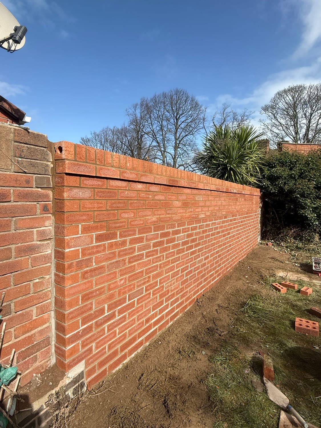 Newly built red brick garden wall with a brick-on-edge coping and neatly struck joints