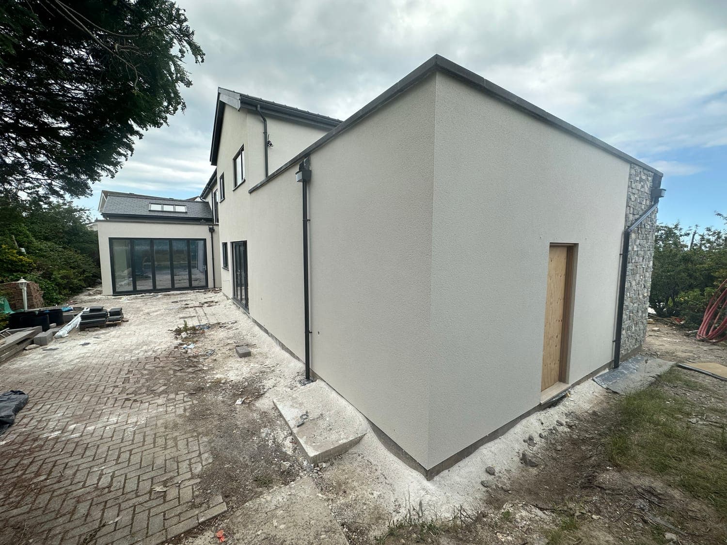 New build in white monocouche render, showing the crisp arris at the corner of the gable