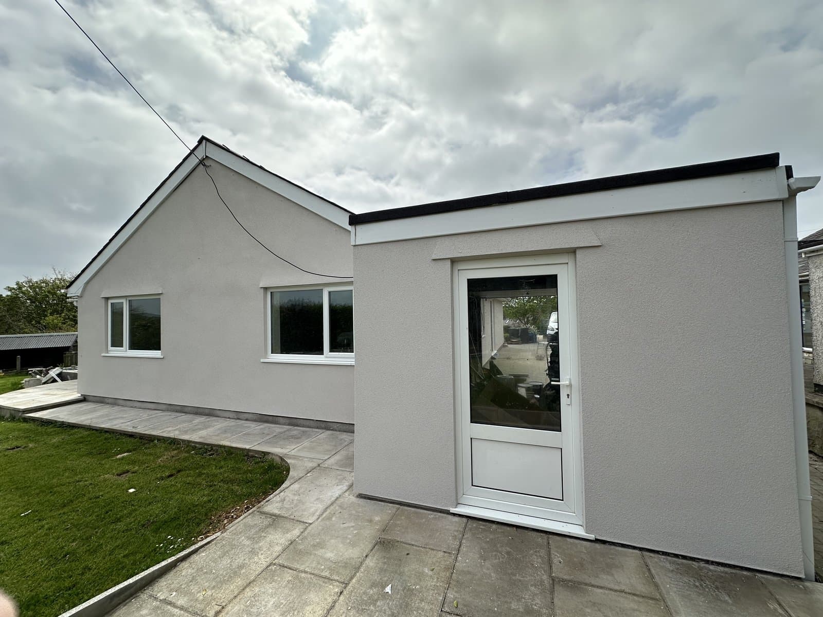 Bungalow extension finished in pale grey silicone render, with white uPVC door and windows