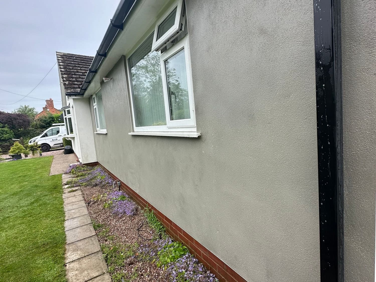 Bungalow side elevation finished in smooth grey sand and cement render, flat and even along its full length