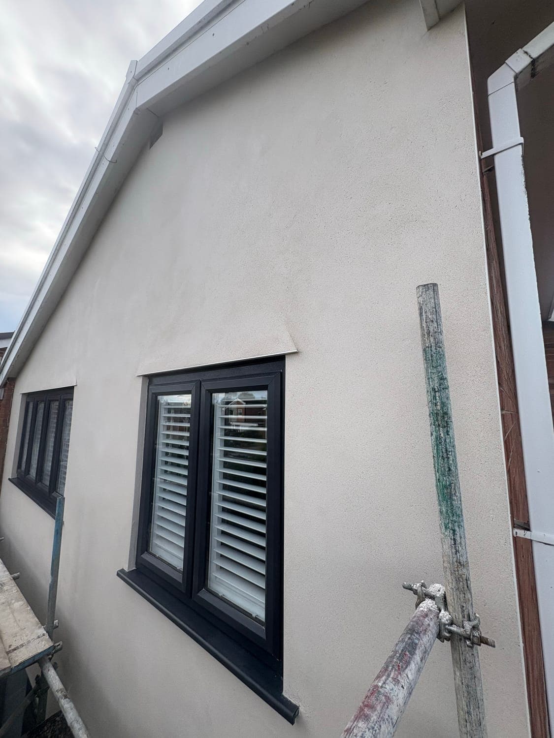 Gable end in smooth sand and cement render, hand-finished flat around the window reveal